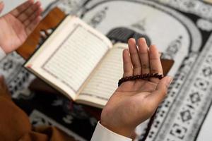 person praying in mosque with Quran book background photo