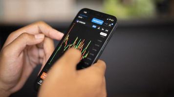 Surabaya, Indonesia 02 04 2023. hands holding smartphone with stock exchange chart photo