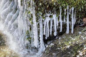 Frost and small icicles on a stone in the river. Spring thaw. photo