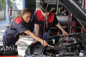 dos profesional automotor mecánico socios cheque y reparar un ev coche batería y híbrido motor a un mantenimiento cochera, experto eléctrico vehículo servicio, y fijación ocupaciones auto industria. foto