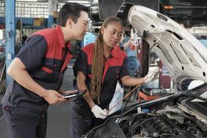 Male professional automotive supervisor advises and inspects Black female mechanic worker about liquid engine oil at car garage, service maintenance, and fixing specialist occupations auto industry. photo