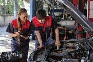 dos profesional automotor mecánico socios cheque y reparar un ev coche batería y híbrido motor a un mantenimiento cochera, experto eléctrico vehículo servicio, y fijación ocupaciones auto industria. foto