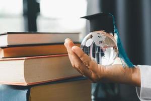 graduado estudiar extranjero programa concepto negro graduación gorra en un globo mapa y libros, representa conocimiento lata ser aprendió en línea en cualquier sitio y en todos lados, incluso en universidades o instalaciones alrededor el mundo. foto