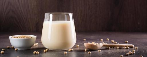 Soy milk in a glass and soybeans in a bowl on the table. Lactose free drink. Web banner photo