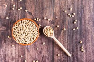 Raw soybean seeds in a bowl, spoon and jar on the table. Source of vegetable protein. Top view photo