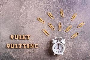 Quiet quitiing wooden letters and a ringing alarm clock. Do nothing beyond your official duties. photo