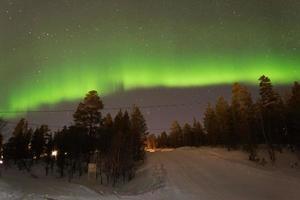 Winter landscape at night with beautiful green northern lights photo