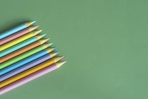 Pastel colored pencils, top view on green background, illustration concept, education and back to school photo