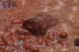 Red beans being cooked showing details of the grains and sausages to taste photo