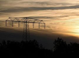 High-voltage power pole with overhead line through which the electricity is transported photo