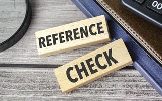 REFERENCE CHECKS. text on wooden blocks on wooden background with office supplies photo