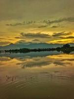 A lake with a mountain standing behind it under the evening clouds photo