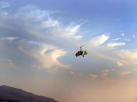 Low angle view of yellow color Gyrocopter flying in the blue sky and dramatic clouds, fun fly, aero sports, skydive, Roto craft, Gyroplane, skydiving, auto Gyro photo