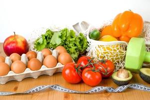 verduras y frutas cerca de pesas y cinta métrica. concepto de deporte y dieta. habitos de comer saludable foto