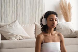 Copiar espacio bandera con sereno africano americano mujer en auriculares meditando bienestar y zen concepto foto