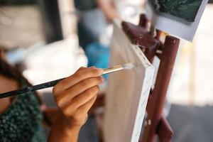 Woman drawing her picture on canvas with oil colors photo