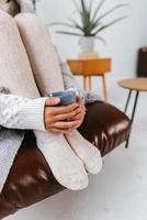 Cropped shot of woman sitting holding a mug at feet photo