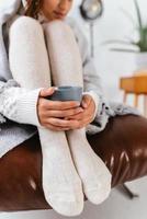 Cropped shot of woman sitting holding a mug at feet photo