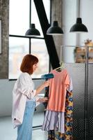 Beautiful young housewife irons clothes with a steamer at home. photo