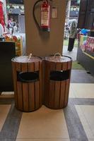 A garbage collection cans with hanged fire extinguisher in the corner of building. Rubbish bin, garbage and waste bin made of wooden material. Clean and protected. Decorating inspiration. photo