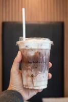 Hand hold ice mocha coffee in a glass with cream photo