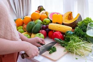 un de la persona manos son visible participación un cuchillo y el cortar vegetales en un corte tablero con Fruta el antecedentes es un blanco cortina foto