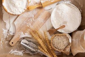 Flour in a bowl and wheat grains with wheat ears on the table, paper background In a rustic kitchen, top view photo