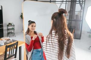 mujer joven se aplica maquillaje en la cara frente al espejo foto