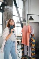 Beautiful young housewife irons clothes with a steamer at home. photo