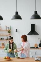 dos amigas cortan fruta en la cocina foto