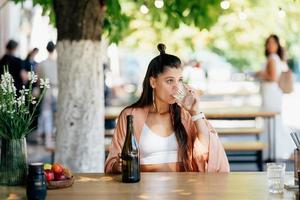 Young woman with a cold drink sitting in a cafe on the street photo