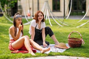 Happy smiling young women eating cherry of the park lawn photo