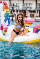 mujer en flotador inflable de colchón de juguete de unicornio en la piscina. foto