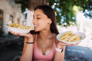 Young women hold french fries on white plates. Street cafe photo