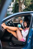 Young woman sitting in a car and holding a globe photo