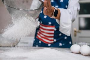 Woman's hands sifting flour through sieve. Selective focus. photo