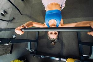 Woman doing exercises with barbell on a bench press training photo