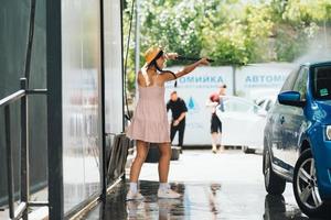 Brunette from a high-pressure hose washes the car photo