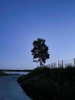 Trees and white clouds by the river with blue water. River landscape. Reflection of the sky in the river. photo