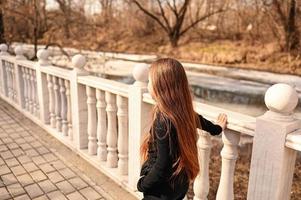 un niña con largo pelo es caminando en el parque. hermosa calentar puesta de sol. un foto de un bonito joven mujer sonriente a el viento en largo Rizado morena cabello.