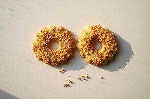 Sand ring with nuts, isolated. Two cookies in the shape of a ring, sprinkled with peanuts. White background photo