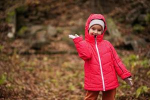 Portrait of baby girl in pink hooded jacket at autumn forest. photo