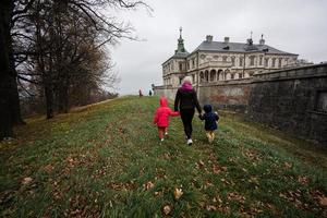 Back of mother holding hands two daughters visit Pidhirtsi Castle, Lviv region, Ukraine. Family tourist. photo