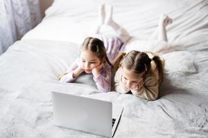 Two girls sisters watching on laptop. Technology and home concept. photo