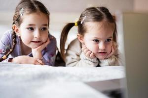 Two girls sisters watching on laptop. Technology and home concept. photo