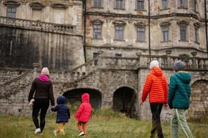 parte posterior de la madre con cuatro hijos visita el castillo de pidhirtsi, región de lviv, ucrania. turista familiar. foto