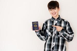 Young teenager boy holding Paraguay passport looking positive and happy standing and smiling with a confident smile against white background. photo