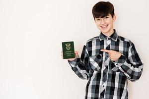 Young teenager boy holding South Africa passport looking positive and happy standing and smiling with a confident smile against white background. photo