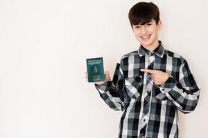 Young teenager boy holding Tunisia passport looking positive and happy standing and smiling with a confident smile against white background. photo