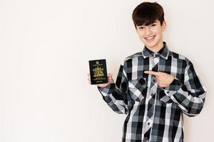 Young teenager boy holding Trinidad and Tobago passport looking positive and happy standing and smiling with a confident smile against white background. photo
